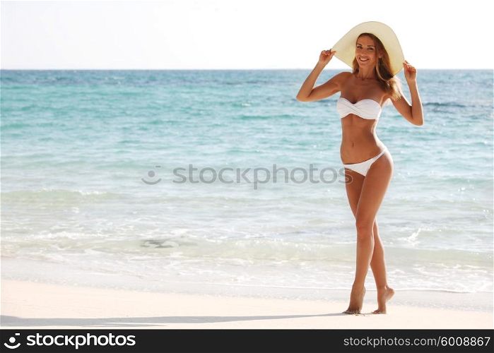 Woman in bikini and sunhat on the beach . Woman on the beach