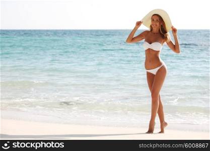 Woman in bikini and sunhat on the beach . Woman on the beach