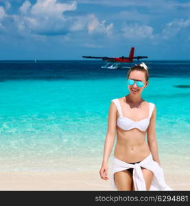 Woman in bikini at tropical beach. Seaplane at background.