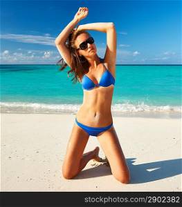 Woman in bikini at tropical beach sitting on her knees