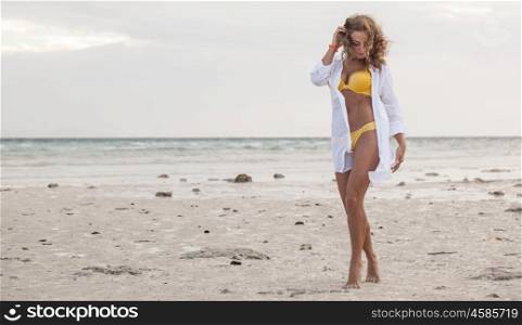 Woman in bikini at tropical beach. Woman in bikini and shirt at tropical beach