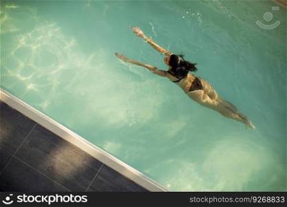 Woman in bikini  floating on water in the pool at summer day