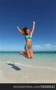Woman in bikini jumping on beach. Beautiful woman in bikini jumping on tropical beach