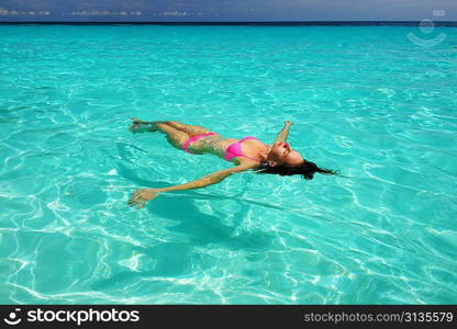 Woman in bikini lying on water at tropical beach