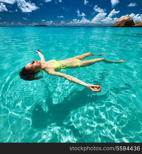 Woman in bikini lying on water at tropical beach