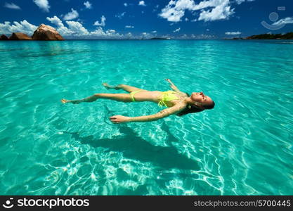 Woman in bikini lying on water at tropical beach