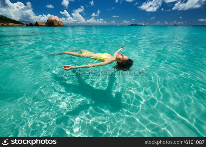 Woman in bikini lying on water at tropical beach