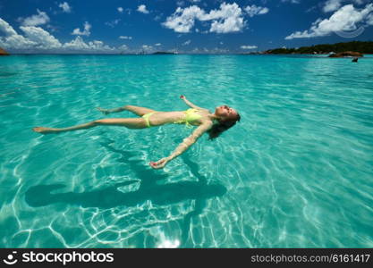 Woman in bikini lying on water at tropical beach