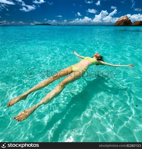 Woman in bikini lying on water at tropical beach