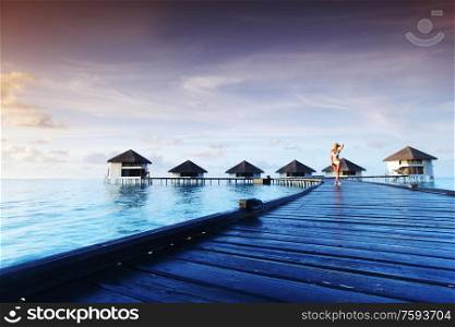 woman in bikini on a bridge home sea and the maldivian sunset on the background. woman in bikini on maldivian sunset