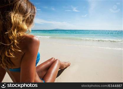 Woman in bikini on beach. Beach holidays woman in bikini enjoying summer sun sitting in sand looking at sea