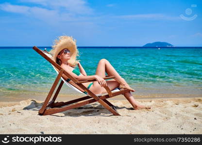 Woman in bikini on beach sitting in lounger chair, Sithonia, Greece