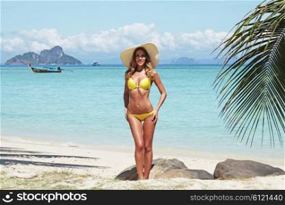 Woman in bikini on beach . Woman in bikini and sunhat on a tropical beach