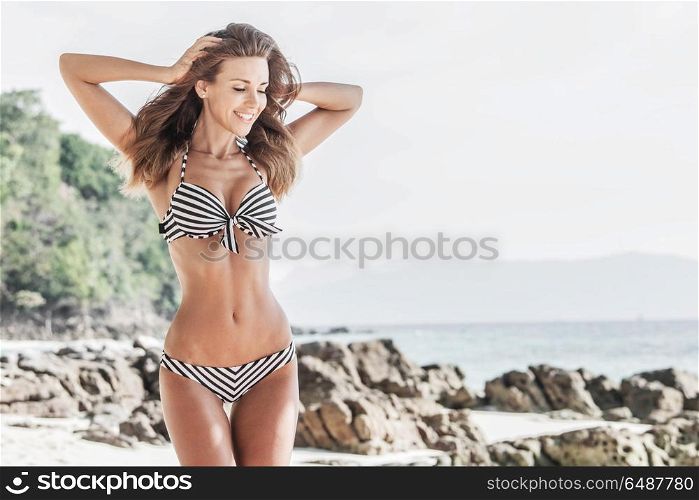 Woman in bikini on tropical beach. Woman in bikini walking on tropical beach, sea and mountains on background