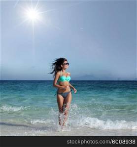 Woman in bikini run to beach. Young attractive woman in bikini run from sea to beach