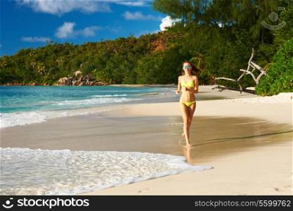 Woman in bikini running at tropical beach at Seychelles