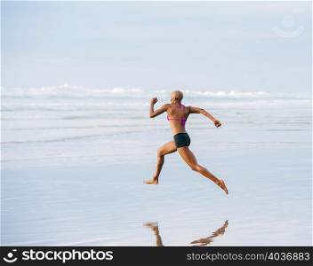 Woman in bikini sprinting on beach