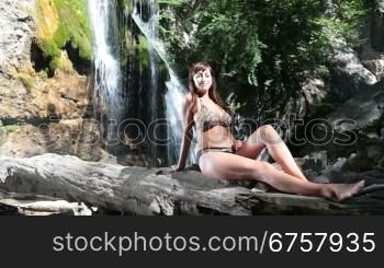 woman in bikini sunbathing near a waterfall