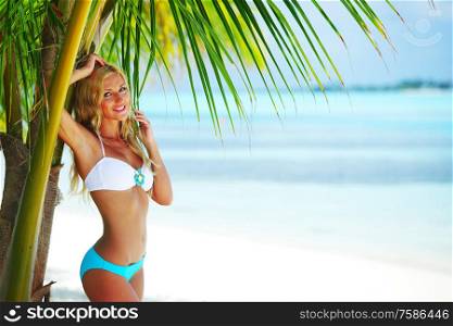 Woman in bikini under palm tree on blue sea background. Woman in bikini under palm