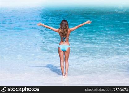 Woman in bikini walking to sea. Beautiful woman in bikini walking to blue tropical sea