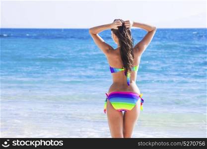 Woman in bikini walking to sea. Beautiful woman in bikini walking to blue tropical sea