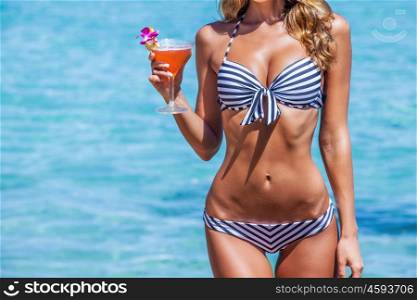 Woman in bikini with cocktail. Beautiful slim woman in bikini with cocktail at seaside