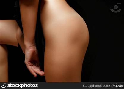 woman in black jacket on naked body posing on black background covering genitals