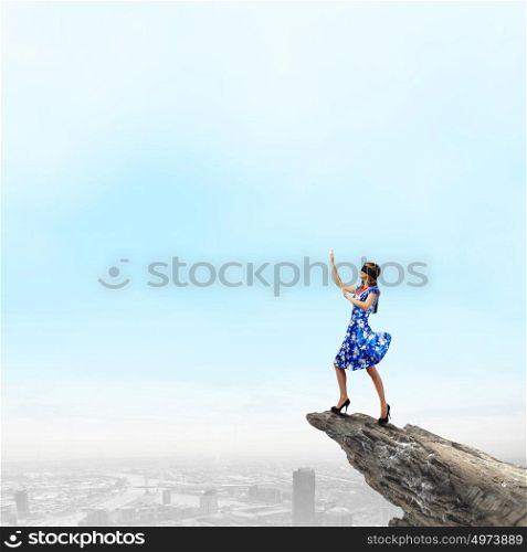 Woman in blindfold. Young woman in blue dress standing on mountain edge