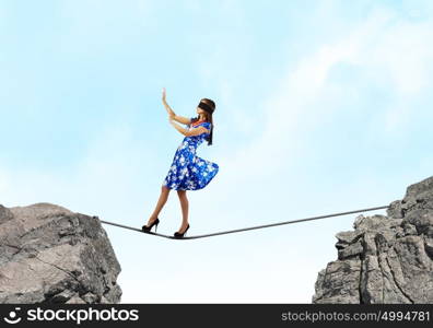 Woman in blindfold. Young woman in blue dress standing on mountain edge