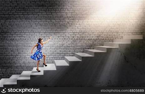 Woman in blindfold. Young woman in blue dress walking on ladder
