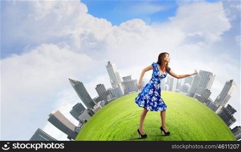 Woman in blue dress. Young woman in blue dress walking on green globe