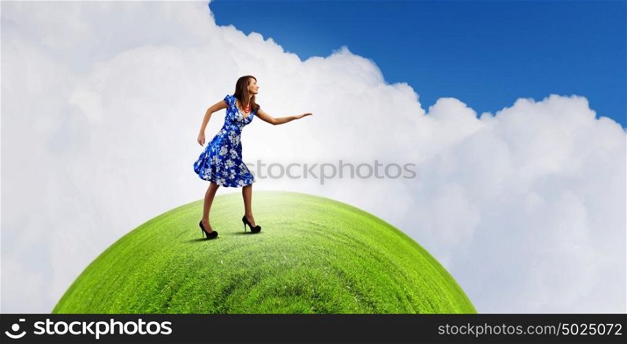Woman in blue dress. Young woman in blue dress walking on green globe