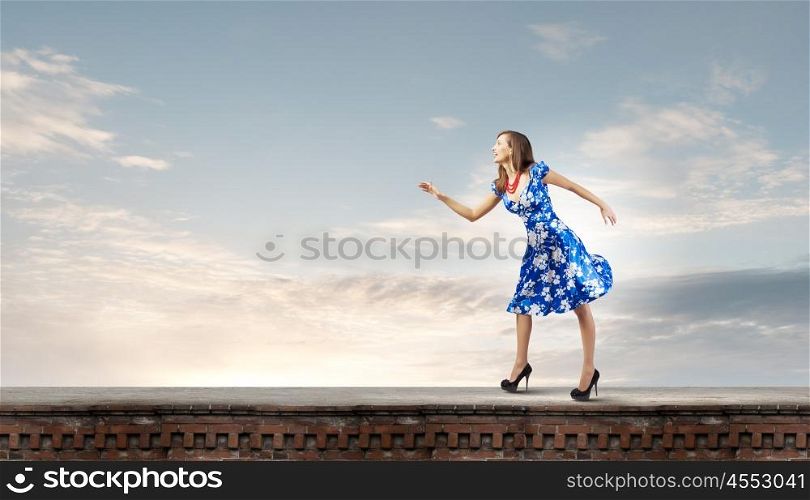 Woman in blue dress. Young woman in blue dress walking on roof of building