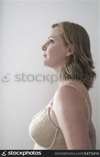 Woman in bra looking away over gray background