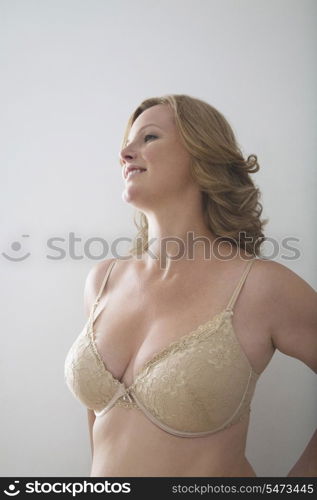 Woman in bra standing against gray background