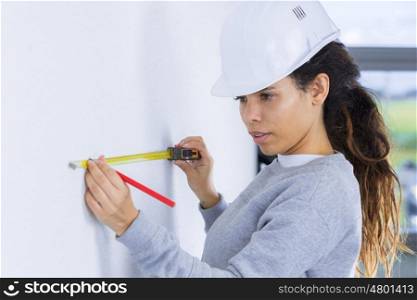 woman in builder uniform draing a plan on a wall