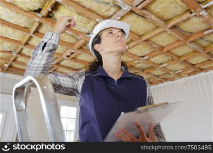 woman in builder uniform on ladder indoor
