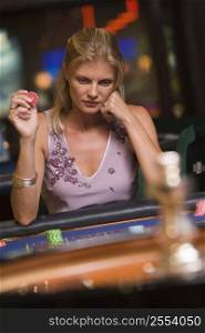 Woman in casino playing roulette and holding chip (selective focus)