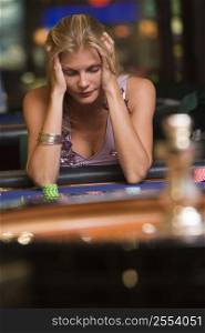 Woman in casino playing roulette and losing (selective focus)