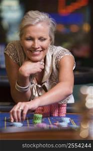 Woman in casino playing roulette and smiling (selective focus)
