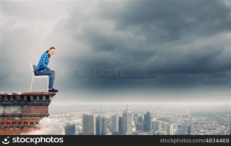 Woman in chair. Young woman in shirt sitting in chair on building roof