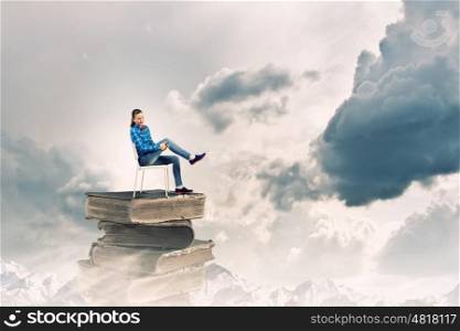 Woman in chair. Young woman in shirt sitting in chair on pile of books