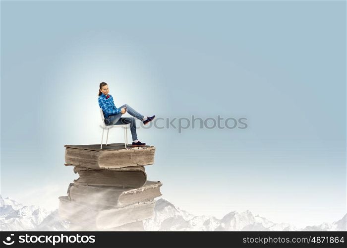 Woman in chair. Young woman in shirt sitting in chair on pile of books