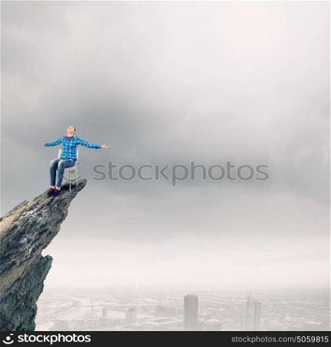 Woman in chair. Young woman in shirt sitting in chair on rock top