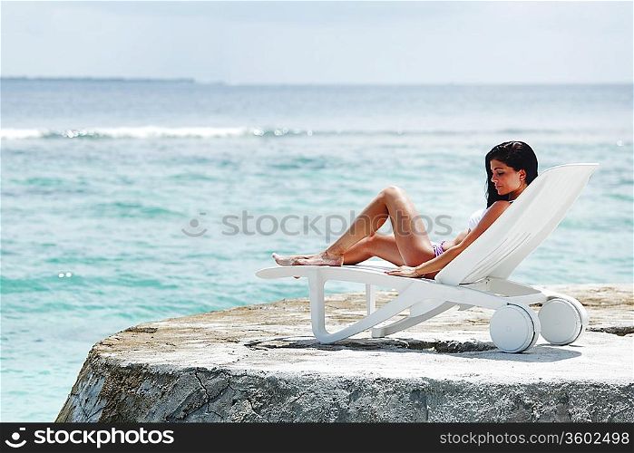 Woman in chaise-lounge near sea