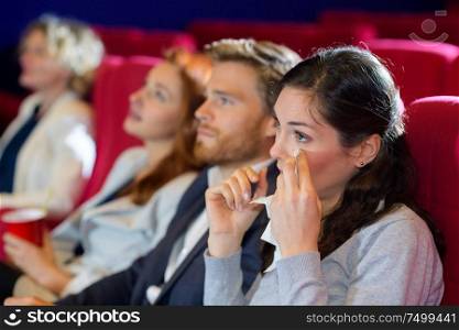 woman in cinema drying eyes with tissue