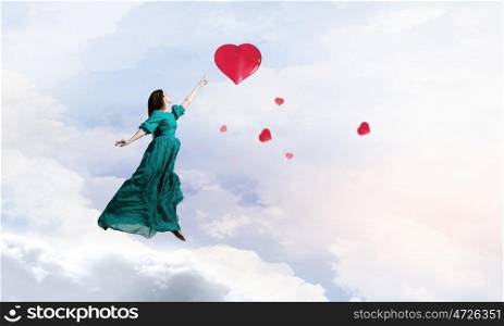 Woman in cloudy sky. Elegant woman in green long dress walking on clouds