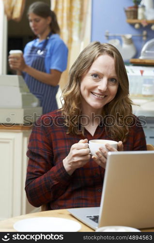 Woman In Coffee Shop Using Laptop Computer