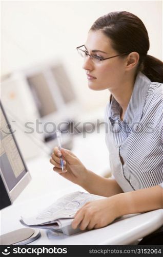 Woman in computer room circling items in a newspaper