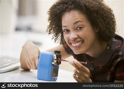 Woman in computer room using pencil sharpener and smiling